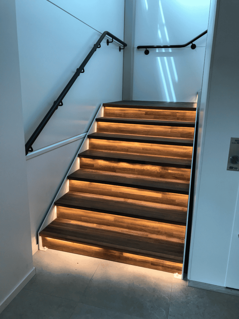 Contemporary wooden staircase with integrated lighting and safety handrails.