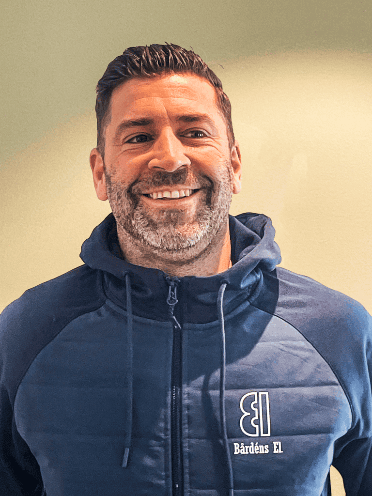 Man smiling in Bårdens El branded hoodie, close-up portrait.